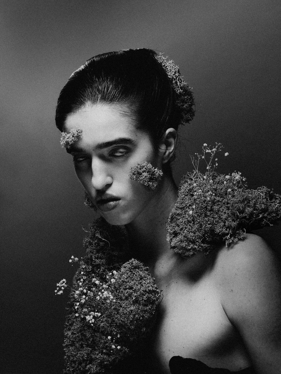 Black and white portrait with moss and flowers worn as hair and makeup