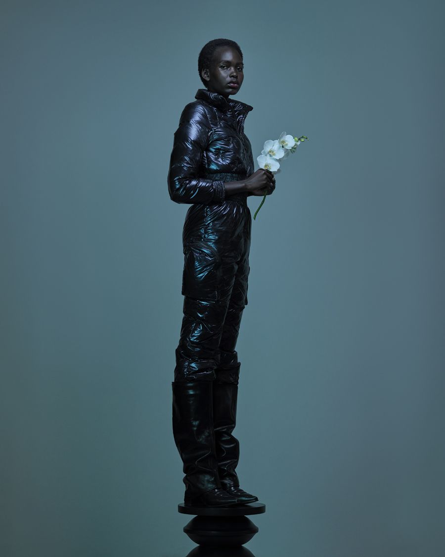 Fashion portrait of a model holding a white orchid in a glossy black suit